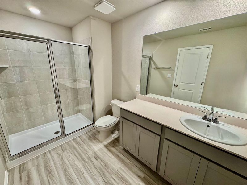 Full bathroom featuring a shower stall, vanity, and wood finished floors