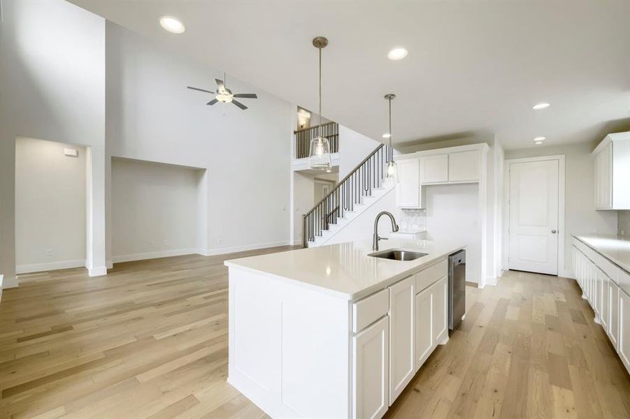 Spacious kitchen island with a stainless steel sink, dual pendant lighting, and white cabinetry Spacious kitchen island with a stainless steel sink, dual pendant lighting, and white cabinetry