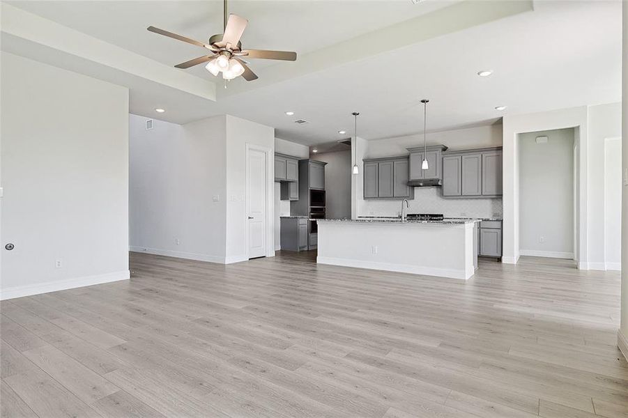 Unfurnished living room with ceiling fan and light wood-type flooring