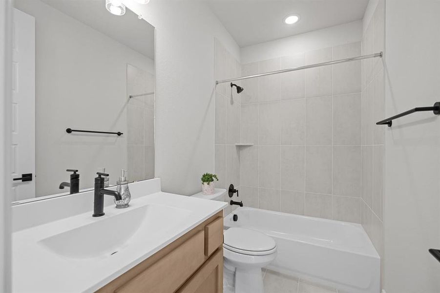 Bathroom featuring a single vanity with a white countertop and light wood-finish cabinetry Bathroom featuring a single vanity with a white countertop and light wood-finish cabinetry