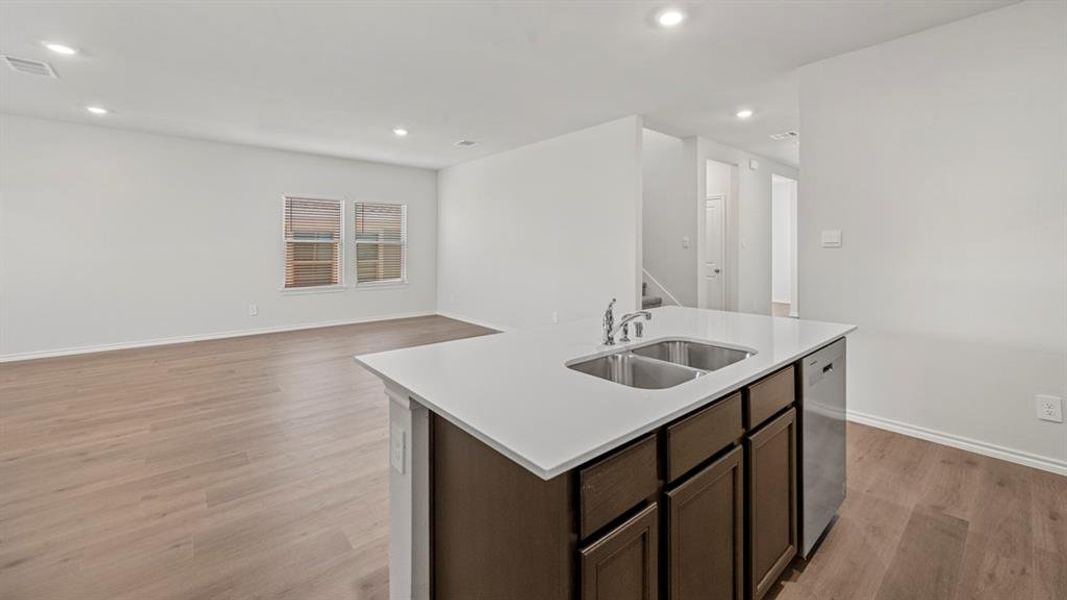 Kitchen with dark brown cabinets, light wood-style floors, an island with sink, open floor plan, and recessed lighting