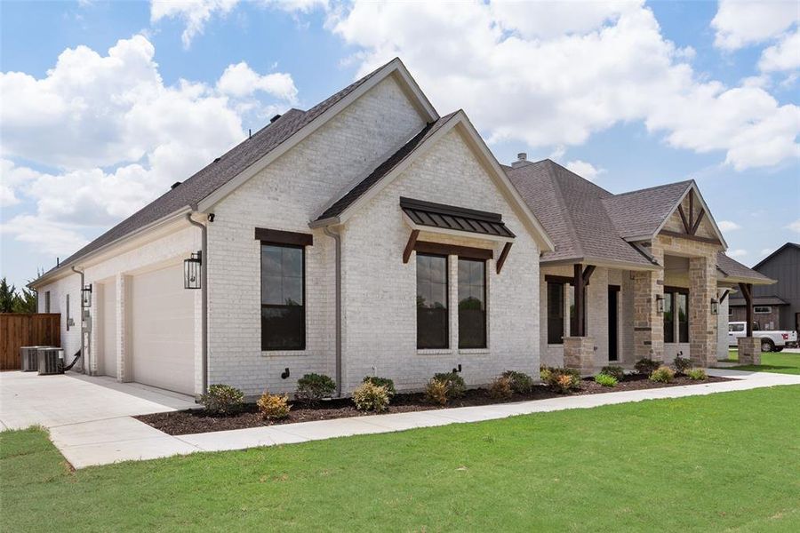 View of front of home with a garage, a front lawn, and central AC unit