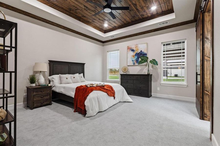 Bedroom with wooden ceiling, light carpet, multiple windows, a raised ceiling, and ceiling fan