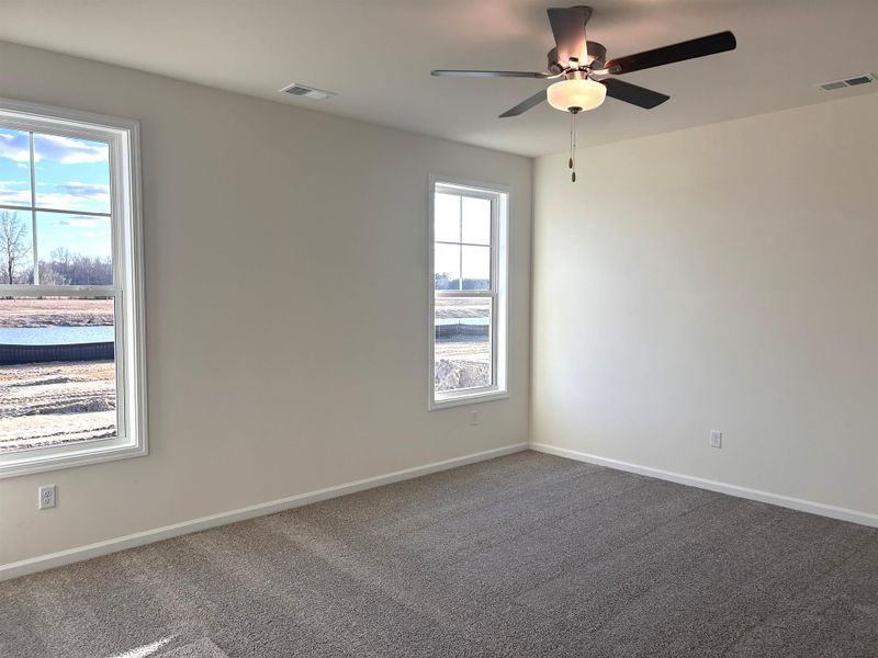 Spare room featuring dark colored carpet and ceiling fan