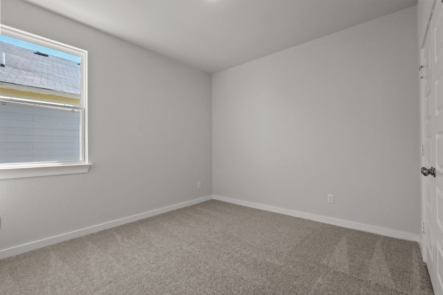 A room with a carpet and a window.