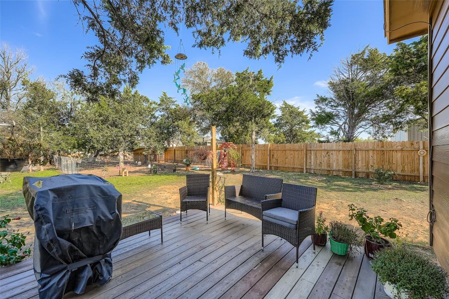 Wooden terrace featuring grilling area, an outdoor hangout area, and a fenced backyard Wooden terrace featuring grilling area, an outdoor hangout area, and a fenced backyard