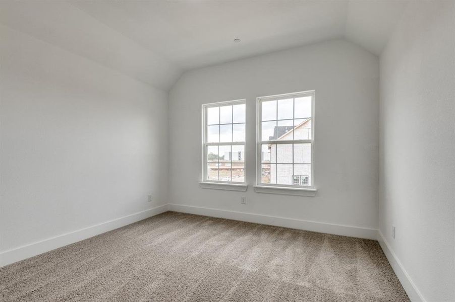 Carpeted spare room with vaulted ceiling