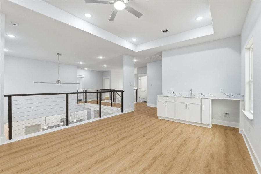 The spacious game room overlooks the main living area and features a sink, additional cabinet storage, and a designated space for a beverage refrigerator.