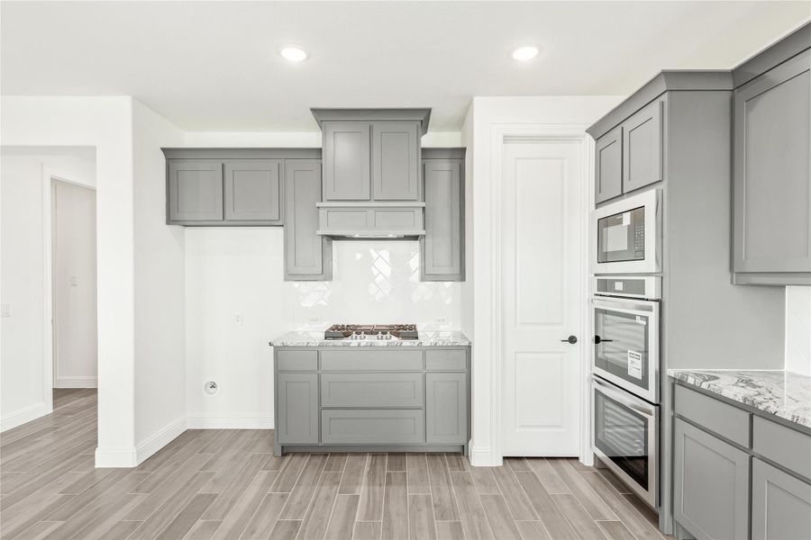 Kitchen with gray cabinets, stainless steel appliances, gas cooktop, and light wood-look tile floors Kitchen with gray cabinets, stainless steel appliances, gas cooktop, and light wood-look tile floors