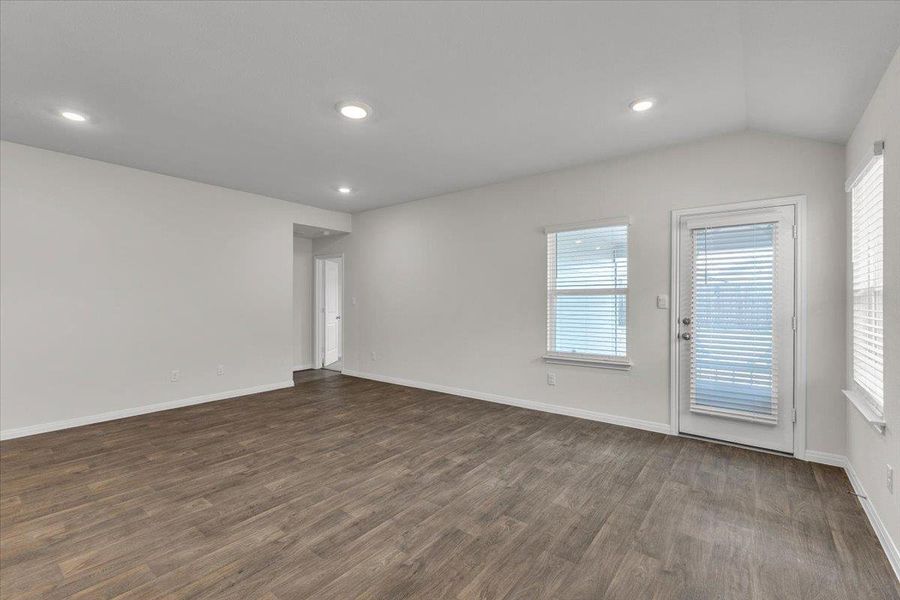 Living area featuring wood-look flooring, light-colored walls, recessed lighting, and a door with an exterior view