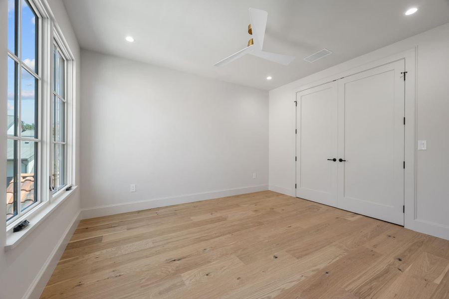 Natural light streams through multi-pane windows onto clean-lined hardwood floors in this versatile space.