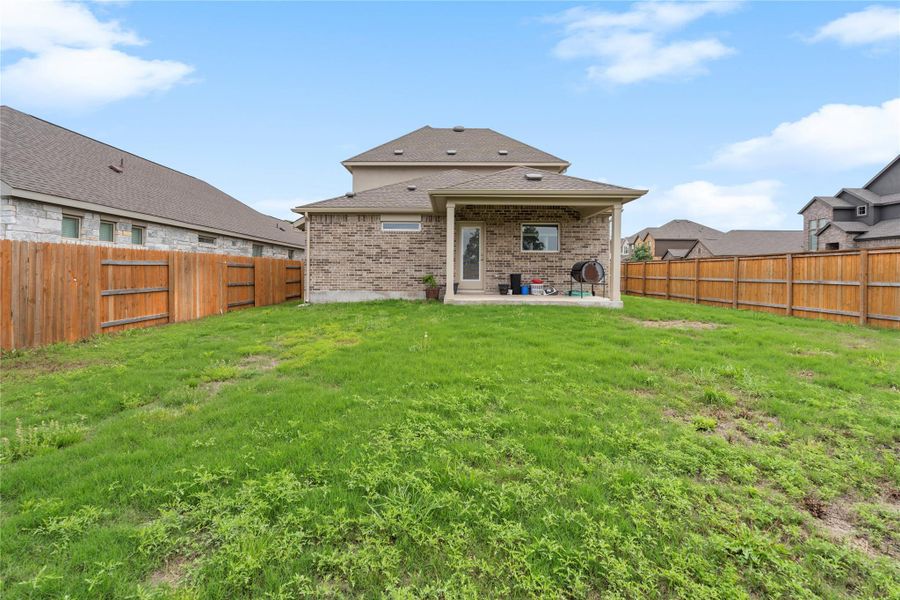 Back of house with a patio, a shingled roof, and brick siding Back of house with a patio, a shingled roof, and brick siding