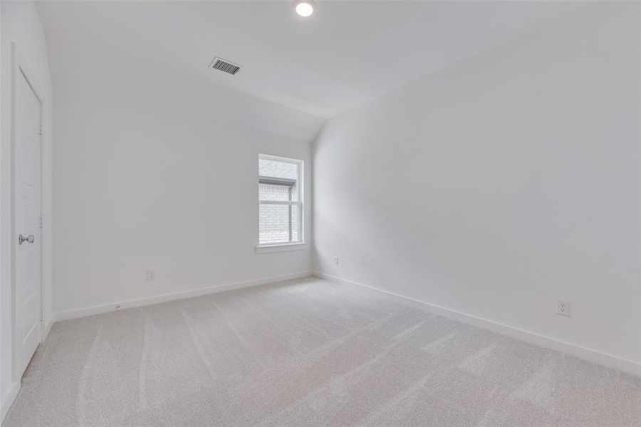 Unfurnished bedroom with light colored carpet, lofted ceiling, and recessed lighting Unfurnished bedroom with light colored carpet, lofted ceiling, and recessed lighting