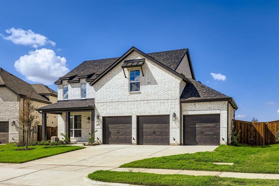 French country inspired facade featuring concrete driveway, brick siding, and roof with shingles