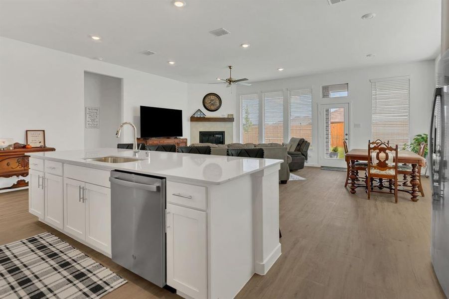 Kitchen with recessed lighting, stainless steel appliances, white cabinetry, open floor plan, and light stone counters