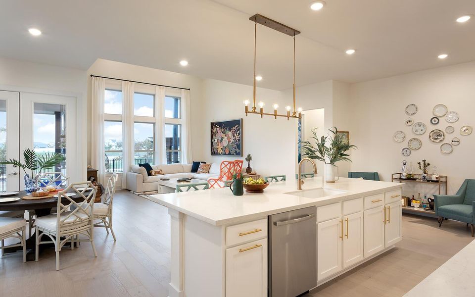 An open floorplan seamlessly connects a sleek kitchen island with bright living and dining areas, all bathed in natural light. An open floorplan seamlessly connects a sleek kitchen island with bright living and dining areas, all bathed in natural light.