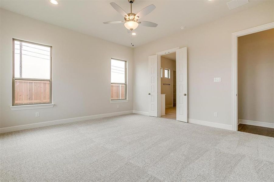 Unfurnished bedroom featuring multiple windows, ceiling fan, and carpet flooring