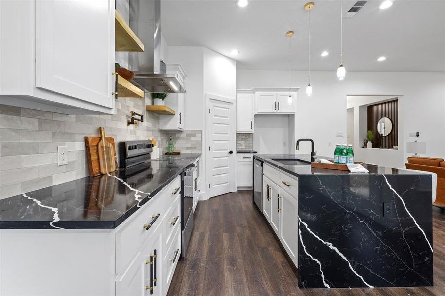 Kitchen with decorative light fixtures, sink, white cabinets, stainless steel appliances, and wall chimney exhaust hood