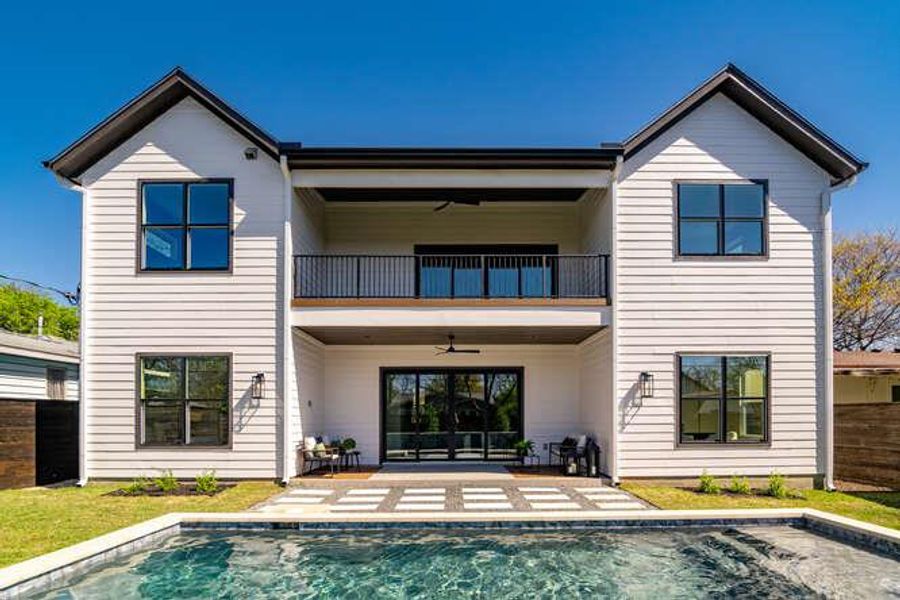 Rear view of property with a ceiling fan, an outdoor pool, a patio, and a balcony Rear view of property with a ceiling fan, an outdoor pool, a patio, and a balcony