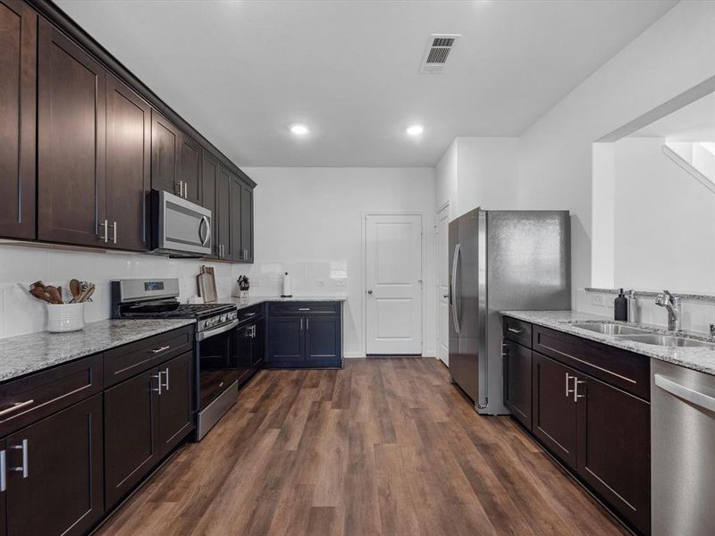 This light and bright kitchen features plenty of  countertop space, dark stained cabinets, a large sink overlooking your family room, and recessed lighting.