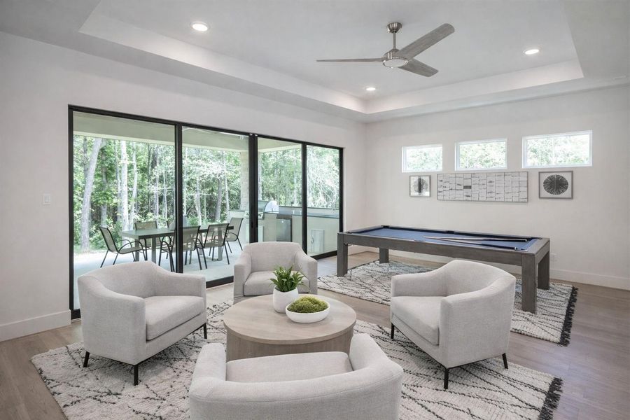 Spacious downstairs game room featuring expansive sliding glass doors that open to serene backyard views and mature trees. Perfect for entertaining of relaxing. This is a Rendering, materials and colors may change.