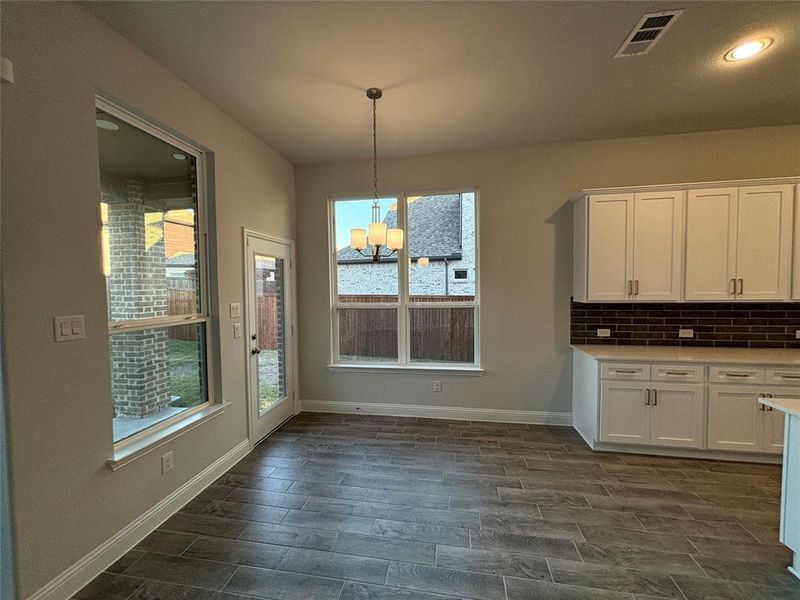 Unfurnished dining area with dark wood-type flooring and a notable chandelier