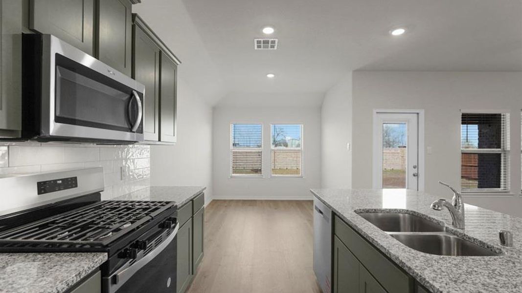 Kitchen featuring granite countertops, stainless steel appliances, dark wood cabinetry, a subway tile backsplash, and wood-finish flooring