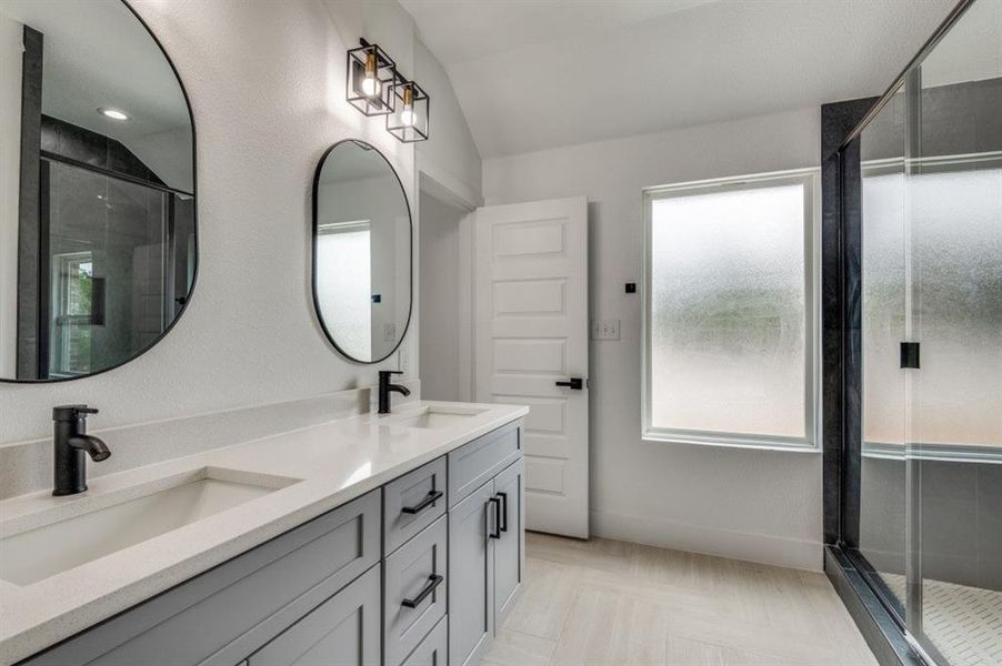 Bathroom featuring a shower with door, vanity, and lofted ceiling