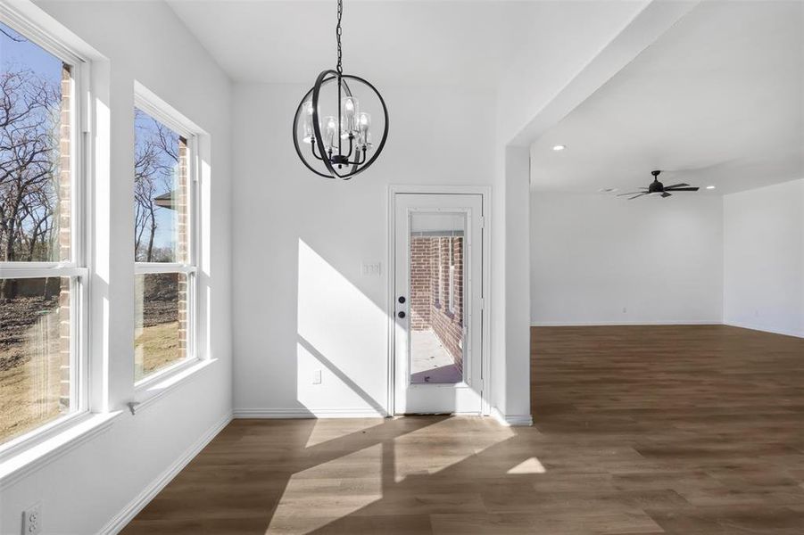 Unfurnished dining area featuring dark wood-type flooring and ceiling fan with notable chandelier