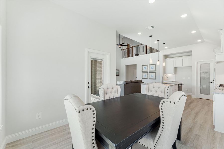 Dining area with dark wood table, tufted white chairs, and open view to kitchen and second-floor loft