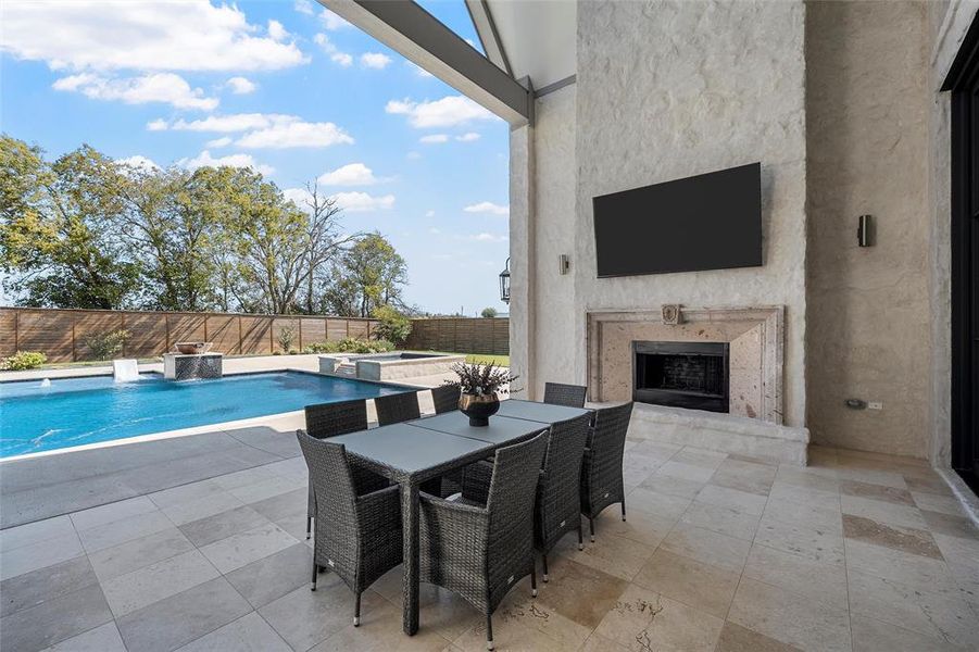 View of swimming pool with an outdoor stone fireplace, a patio, outdoor dining space, and a fenced backyard