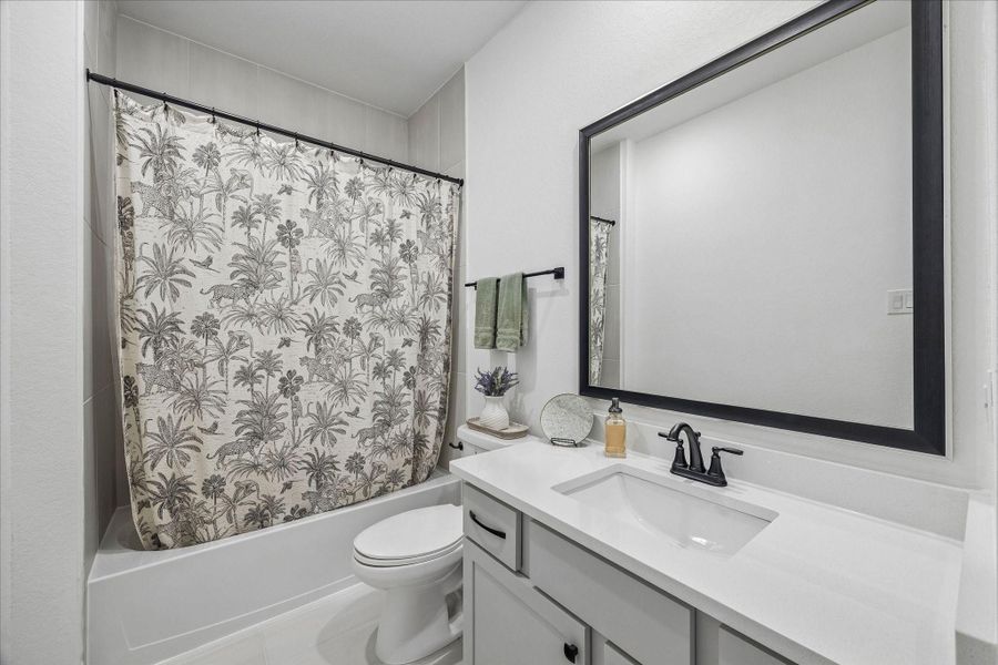 The secondary bathroom features a shower-tub combination with floor-to-ceiling tile, a modern vanity, and thoughtful finishes throughout.