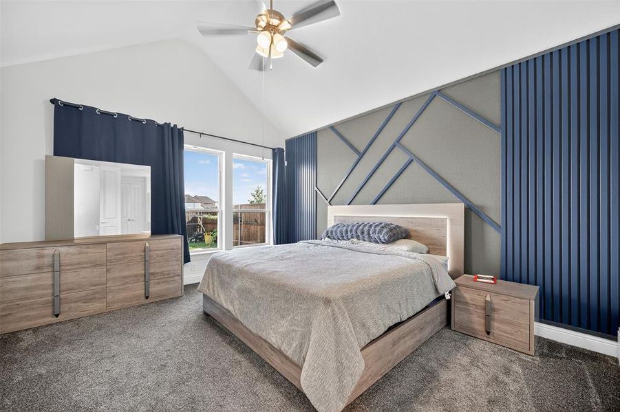 Carpeted bedroom with a ceiling fan and high vaulted ceiling Carpeted bedroom with a ceiling fan and high vaulted ceiling