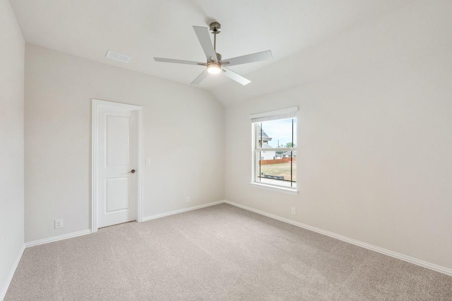 Empty bedroom with vaulted ceiling, ceiling fan, carpet flooring, and a single window