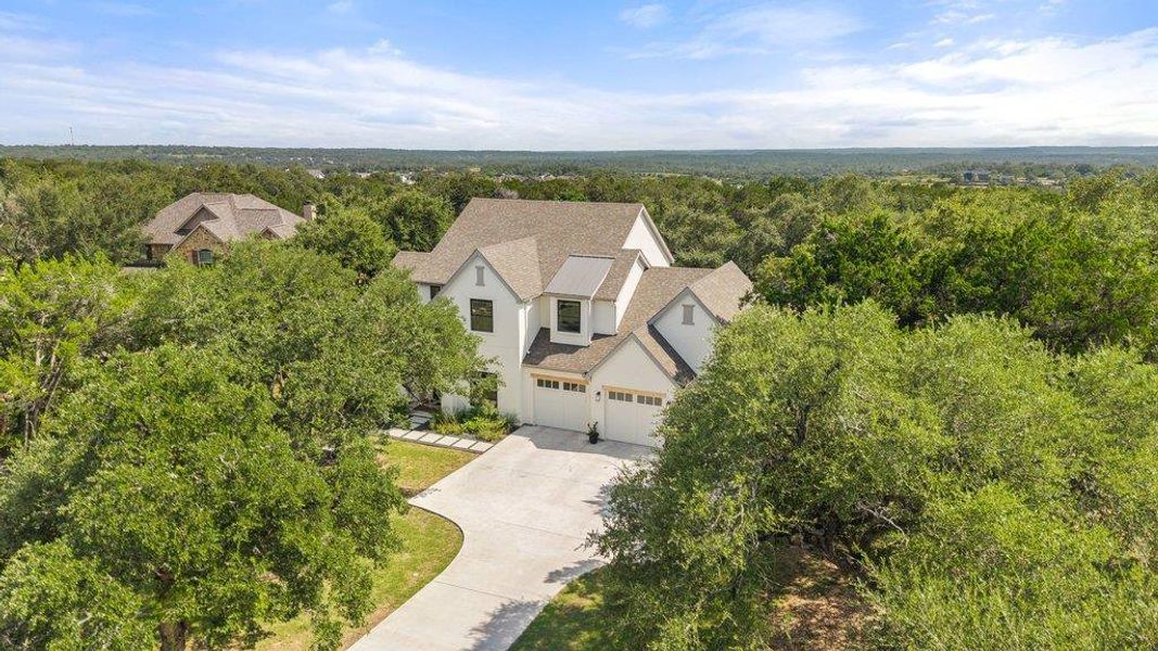 An aerial perspective reveals a contemporary residence nestled amongst a lush, verdant landscape with an inviting driveway leading to the main entrance. An aerial perspective reveals a contemporary residence nestled amongst a lush, verdant landscape with an inviting driveway leading to the main entrance.