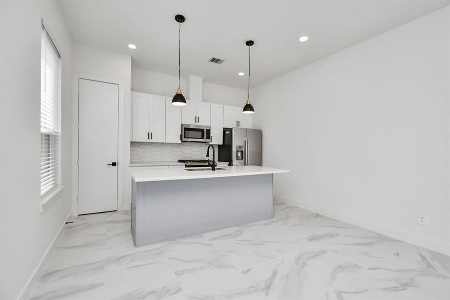 Delight in meal prep or host elegant dinner parties in this tastefully appointed open concept kitchen dining area, enhanced by the soft glow of recessed lighting and elegant light fixtures