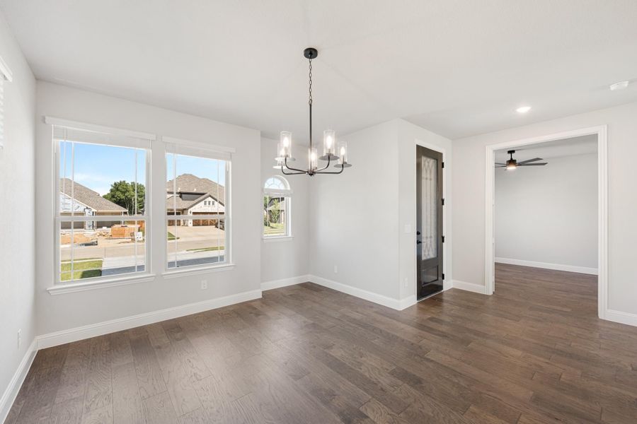 Dining room with dark hardwood floors, chandelier, and large windows overlooking neighborhood Dining room with dark hardwood floors, chandelier, and large windows overlooking neighborhood