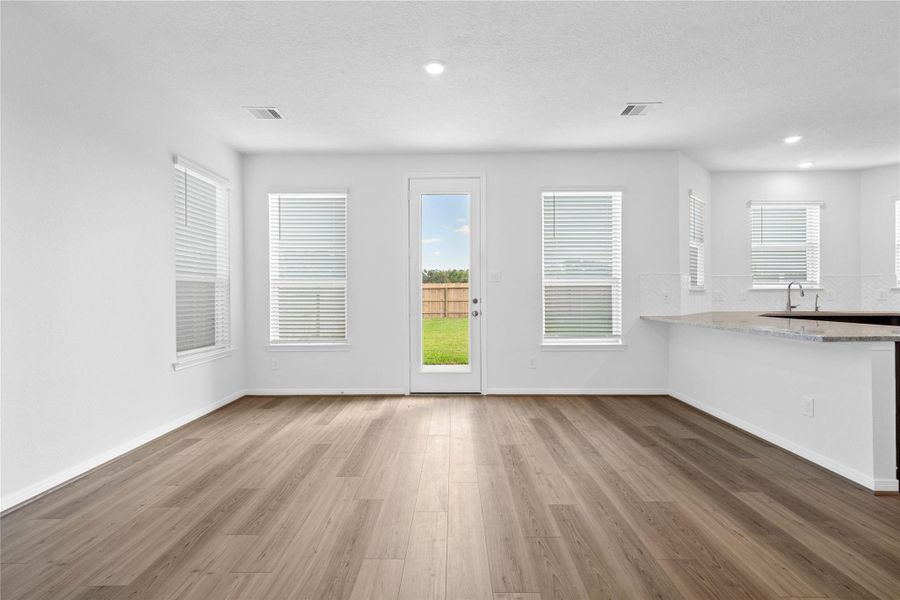 Create lasting memories around the table with family and friends in this inviting dining room! It showcases high ceilings, large windows with privacy blinds, access door to the back patio and yard, vinyl plank flooring, and recessed lighting for a warm and welcoming atmosphere.