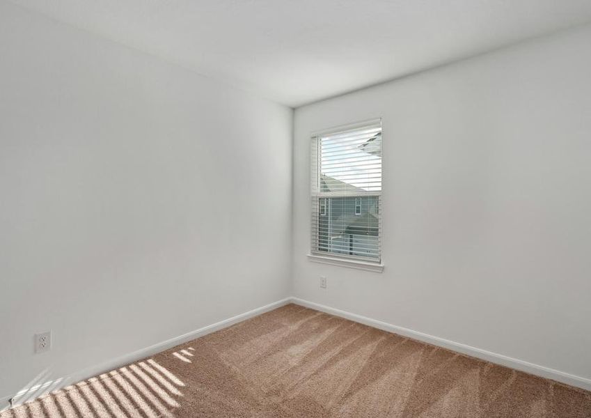 Guest bedroom with tan carpet, a window, and recessed lighting.