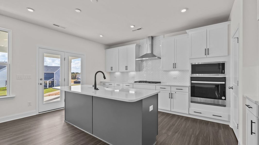Burton Design gourmet kitchen with wall oven & microwave, vented hood, & cooktop. At Lakeside Glen by DRB Homes in York, SC.
