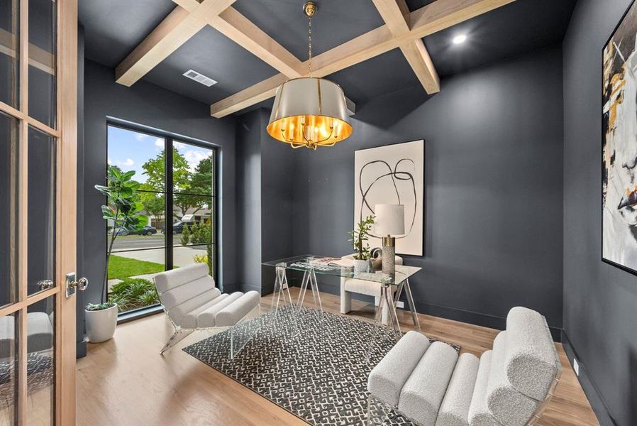 This room features hardwood flooring, a coffered ceiling with recessed lighting, and a large window providing natural light