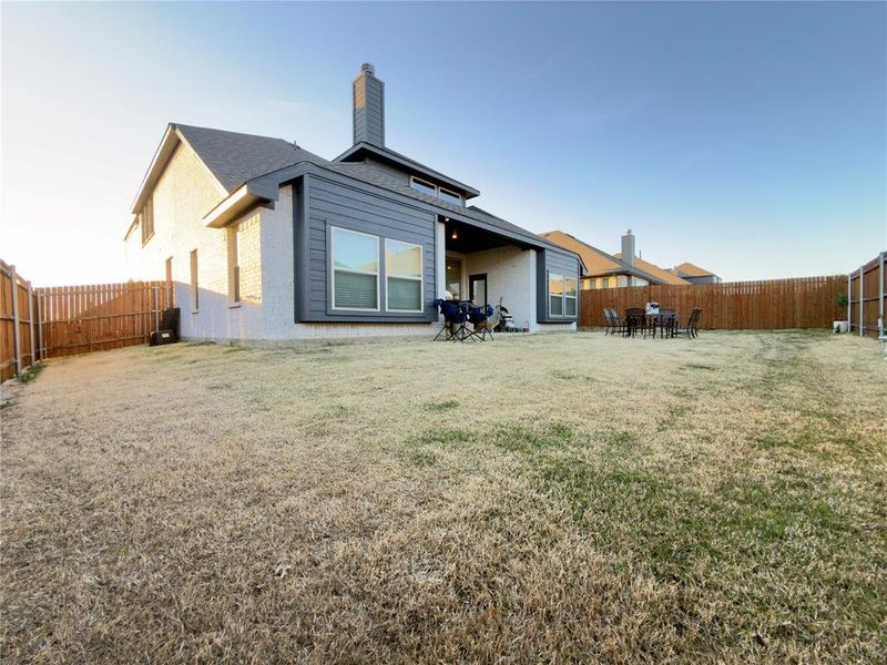Rear view of house featuring a fenced backyard, a patio, and a chimney
