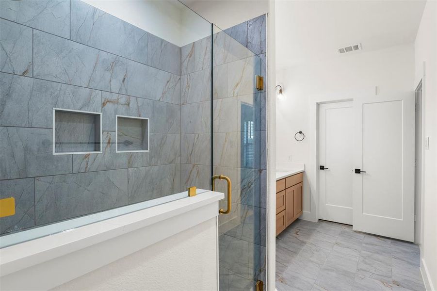 Bathroom featuring a shower stall, vanity, and light marble finish floors