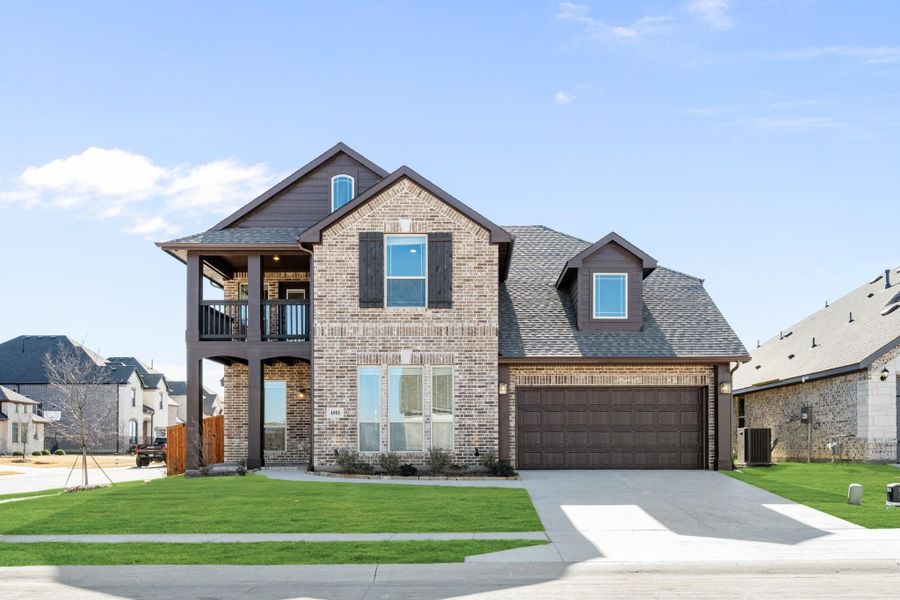 Two-story brick home with second-floor balcony, two-car garage, and manicured front lawn