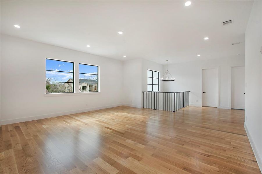 Empty room featuring light hardwood / wood-style floors and an inviting chandelier