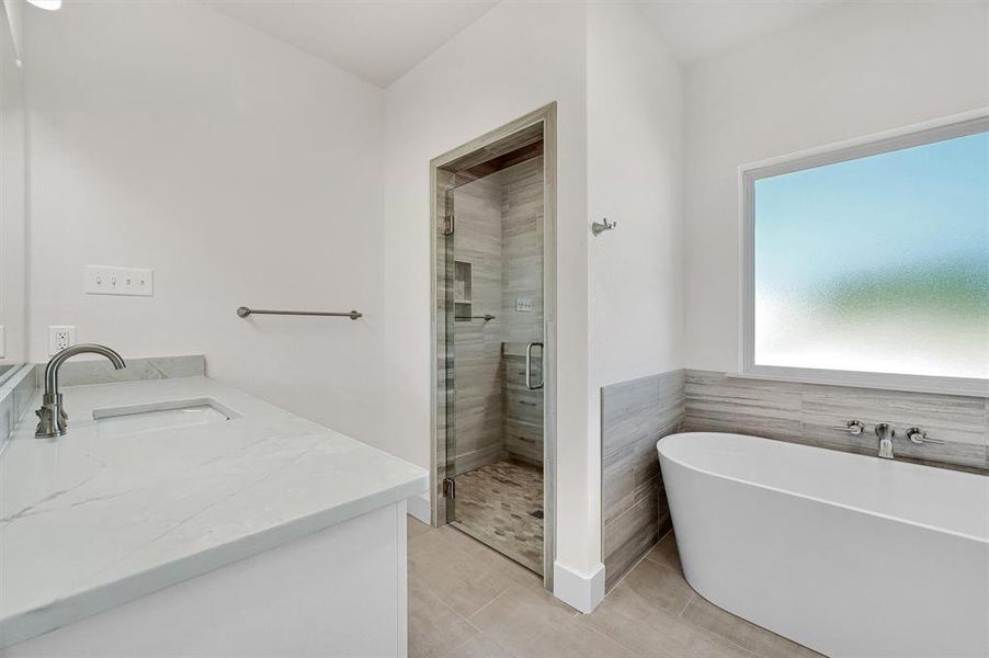 Bathroom featuring tile patterned floors, separate shower and tub, and vanity