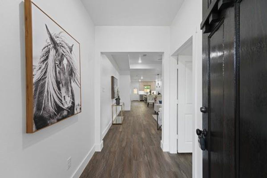 Hallway featuring wood-finish flooring, white walls, recessed lighting, and a dark wood barn door Hallway featuring wood-finish flooring, white walls, recessed lighting, and a dark wood barn door