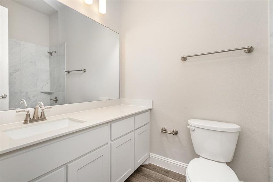 Bathroom featuring vanity, tiled shower, and dark wood-style flooring Bathroom featuring vanity, tiled shower, and dark wood-style flooring