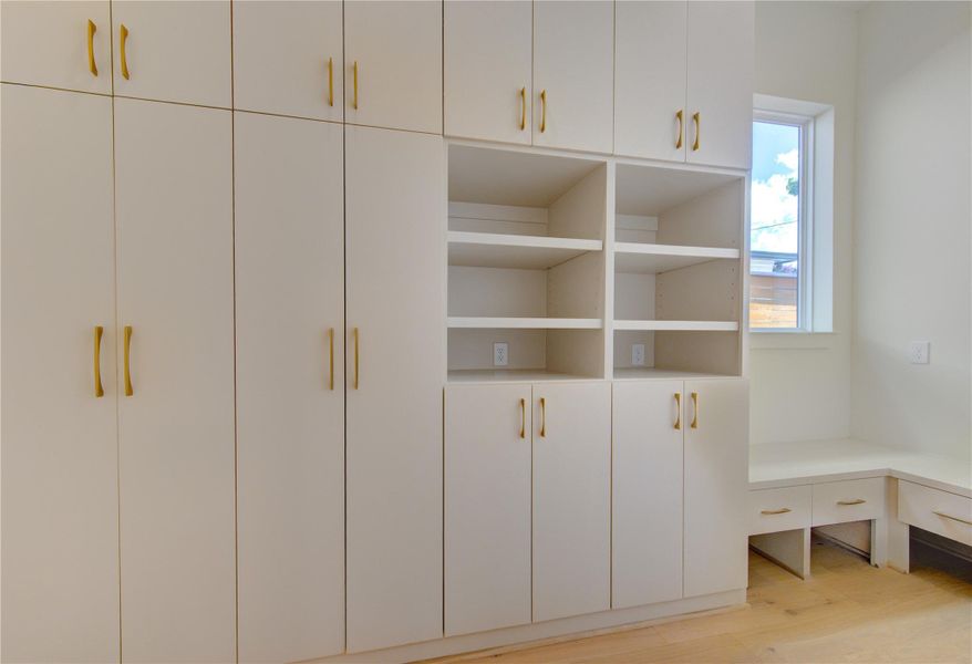 Designed for everyday convenience, the custom mudroom provides a stylish and highly functional transition from the garage into the home. Featuring extensive built-in cabinetry, open storage, and a dedicated drop zone, this thoughtfully designed space keeps daily essentials organized while maintaining the home's clean, sophisticated aesthetic.