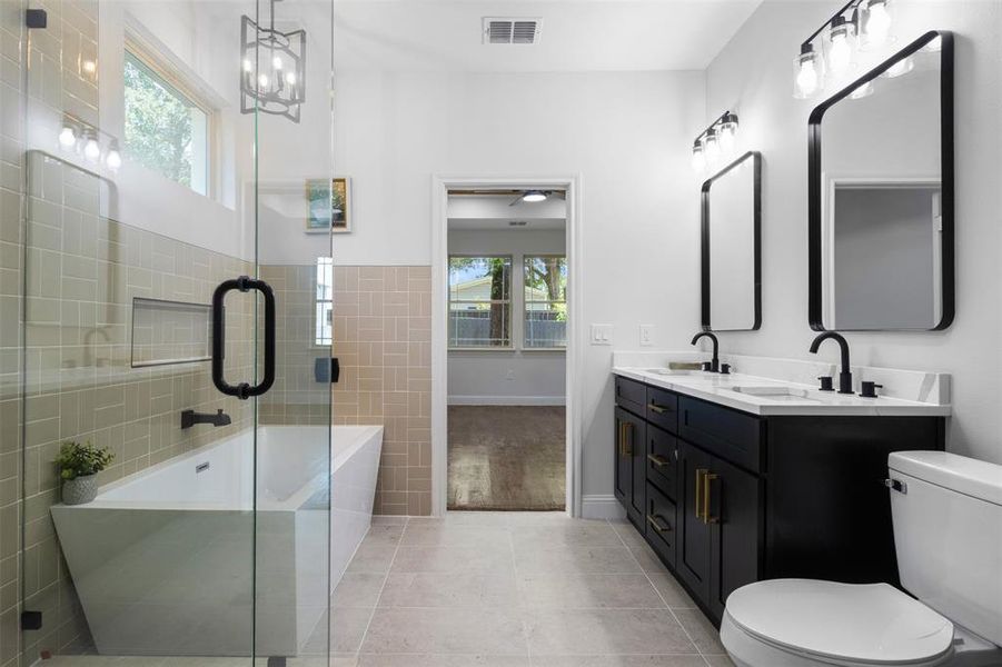 Full bathroom featuring healthy amount of natural light, a bathtub, double vanity, and tile patterned floors Full bathroom featuring healthy amount of natural light, a bathtub, double vanity, and tile patterned floors